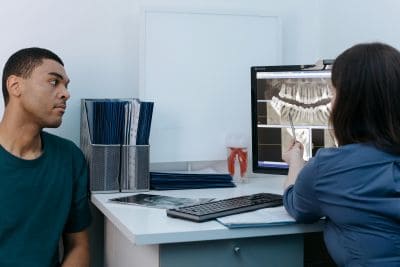 A dentist reviews X-rays with a patient, highlighting why fall is the perfect time for your routine dental cleaning. - Dentistry For You | Broken Arrow Dentist | Broken Arrow, OK Dentist showing a patient their dental X-ray and discussing why fall is a great time for your routine dental cleaning
