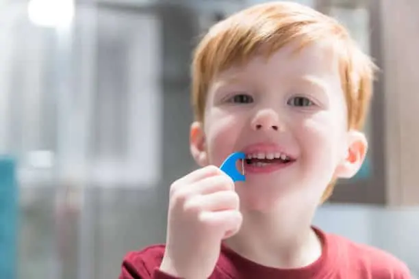 Young boy with red hair brushing his teeth.