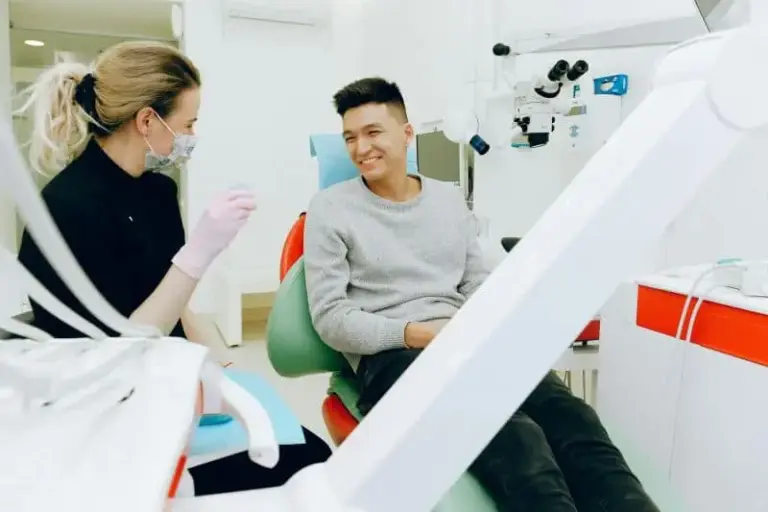 Clinician in a mask attending to a young man seated in the dental chair.