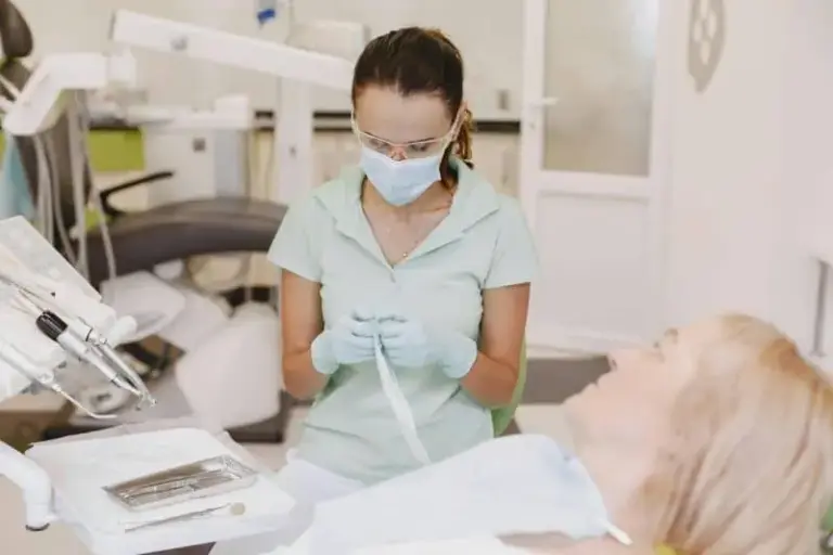 Hygienist in a mask working on an older patient reclined in the chair.
