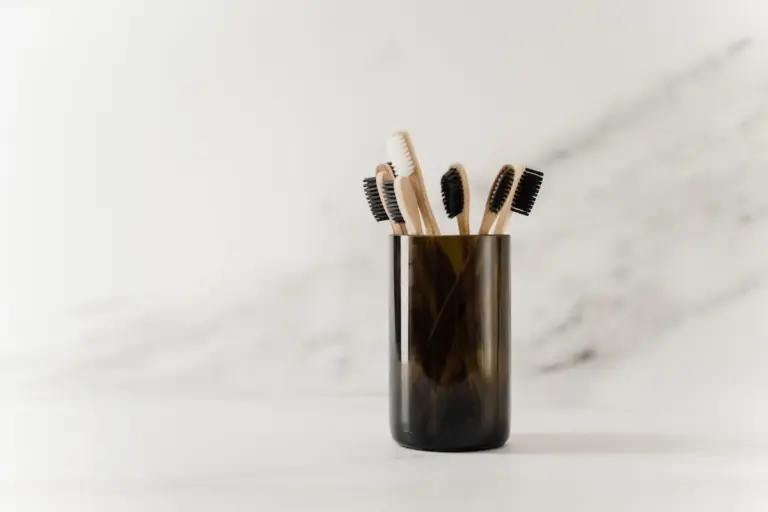 Bamboo toothbrushes in a ceramic holder on a marble surface.