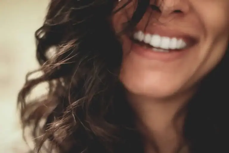 Close-up of a broad smile with dark curly hair.
