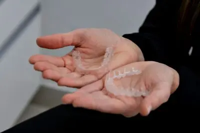 Hands holding a clear aligner over a lather of soap.