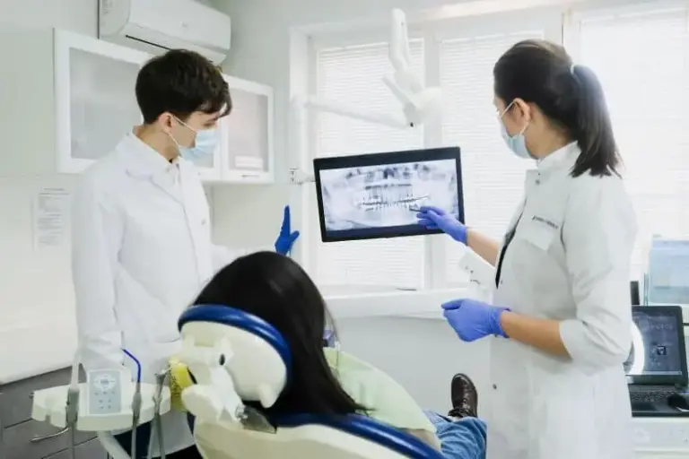 Clinicians discussing a scan on a monitor while a patient lies in the chair.