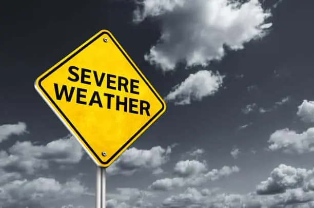 Yellow road sign reading SEVERE WEATHER against a bank of storm clouds.
