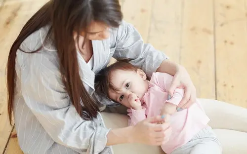 Mother holding and playing with her baby.