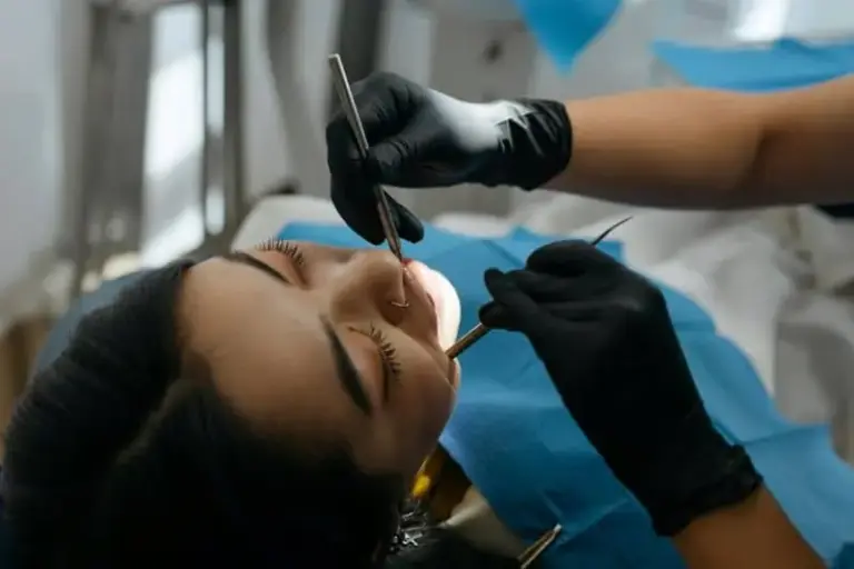 Gloved hands holding a mirror and probe over a reclining patient.