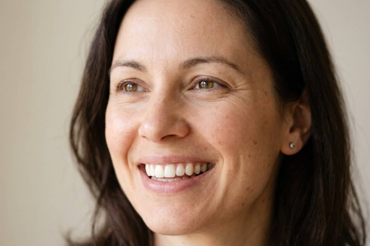 Close-up portrait of a smiling woman with brown hair and warm brown eyes.