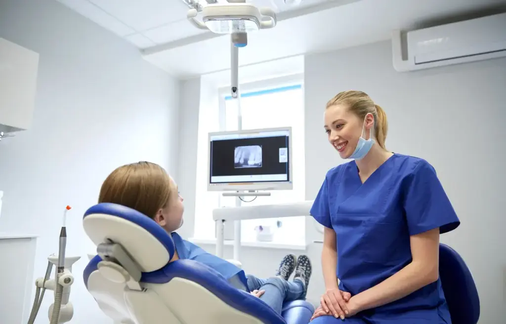 A child sitting in a dental chair with a clinician beside them